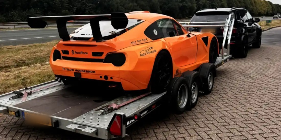 Oranje raceauto vastgesjord op onze open trailer